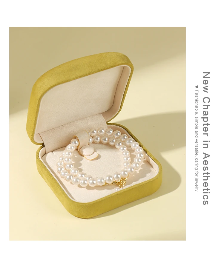 ALT TEXT 175 CHARS Yellow suede jewelry box holding pearl necklace — new aesthetic chapter for fashion minimalist jewelry packaging. Soft velvet interior cushions pearls and chains by jewelry box supplier. Copy